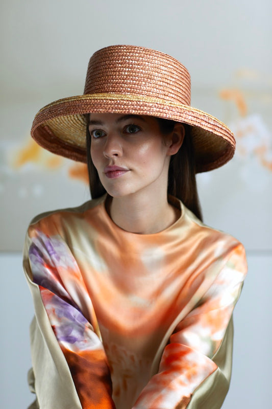 Model mit Strohhut und floral bedruckte Satinbluse in orange und lila Tönen