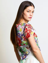 dunkelhaariges Model schaut über die Schulter zurück und trägt ein rotgrün besticktes Pailletten-Oberteil