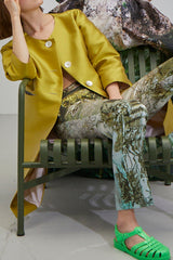 Mantel Box aus lindgrünem Duchesse mit silbernen Perlmutt-Knöpfen kombiniert mit Hose HH in Motiv Japanese Garden kombiniert mit giftgrünen Gummi-Sandalen von Rombaut sitzen auf einem tannengrünen Metall-Sessel
